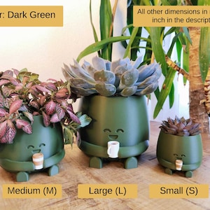 May include: Three dark green ceramic plant pots, small, medium, and large, each with a smiling face, legs, and a small cup. The pots are filled with plants. Text includes "Color: Dark Green" and "All other dimensions in mm and inch in the description".