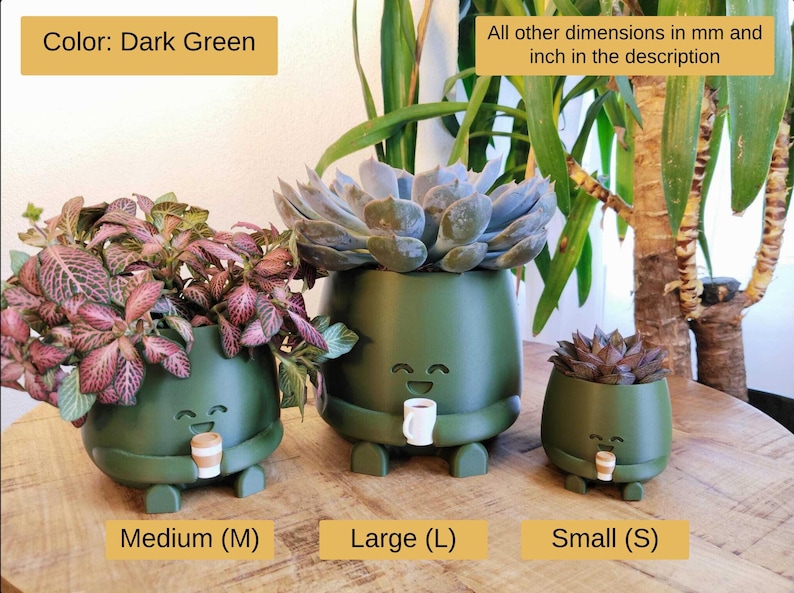 May include: Three dark green ceramic plant pots, small, medium, and large, each with a smiling face, legs, and a small cup. The pots are filled with plants. Text includes "Color: Dark Green" and "All other dimensions in mm and inch in the description".