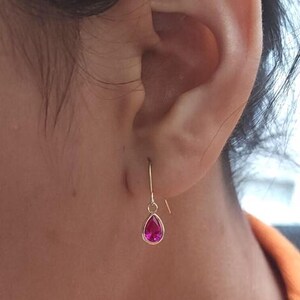 May include: A pair of gold teardrop earrings with a pink gemstone.
