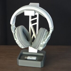 May include: White and gray 3D printed headphone stand with a gray USB dongle on the base.