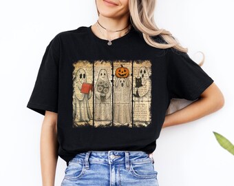 May include: A black short-sleeve t-shirt featuring a graphic print of four ghosts arranged in vertical panels. The ghosts are depicted over a vintage book page background, holding a red book, flowers, a pumpkin, and a black cat.