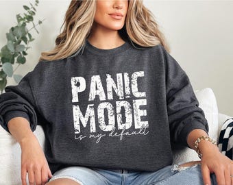 May include: Dark gray sweatshirt with the text "PANIC MODE is my default" in white block letters. The sweatshirt is a crew neck style and appears to be made of a soft material. The text is in a distressed font.