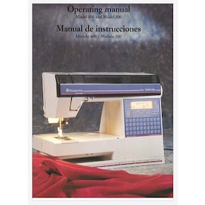 May include: A white sewing machine with a blue and gray control panel. The machine has a digital display and a keyboard. The machine is sitting on a red fabric surface. The text on the cover reads "Operating manual Model 400 and Model 500 Manual de instrucciones Modelo 400 y Modelo 500 Husqvarna COMPUTER".