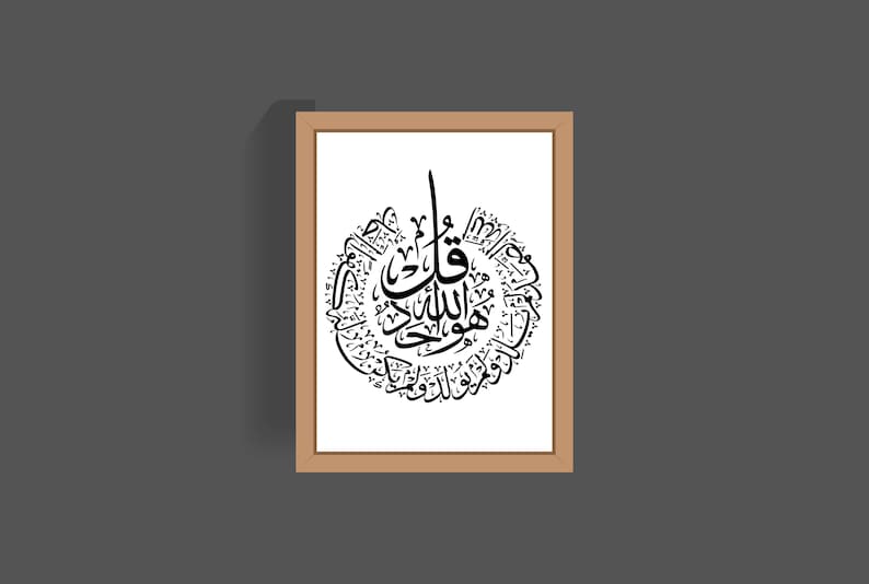 May include: A framed print of black Arabic calligraphy in a circular design on a white background. The calligraphy is in a decorative style and includes the phrase "Allah" in the center.