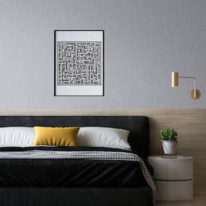 May include: A black and white framed print of Islamic calligraphy hangs on a gray wall above a black headboard bed with a yellow pillow. A small potted plant sits on a white nightstand with a gold wall sconce.