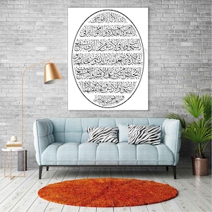 May include: A black and white Islamic calligraphy print in an oval shape on a white background. The print is framed and hanging on a brick wall above a light blue sofa with zebra print throw pillows.