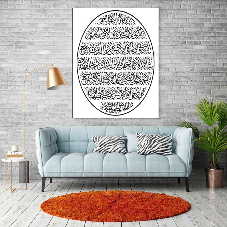May include: A black and white Islamic calligraphy print in an oval shape on a white background. The print is framed and hanging on a brick wall above a light blue sofa with zebra print throw pillows.