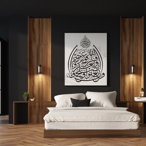 May include: A white bed with white bedding and black pillows in a modern bedroom with dark walls and wooden accents. A black and white calligraphy print hangs on the wall above the bed.