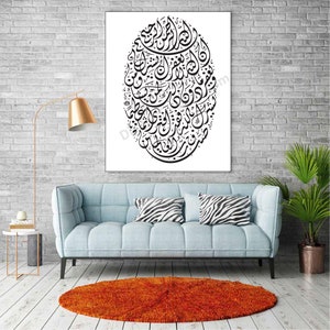 Op de afbeelding: Een zwart-witte islamitische kalligrafie-kunstprint met een cirkelvormig ontwerp met Arabische schrift. De print is ingelijst en hangt aan een witte bakstenen muur.