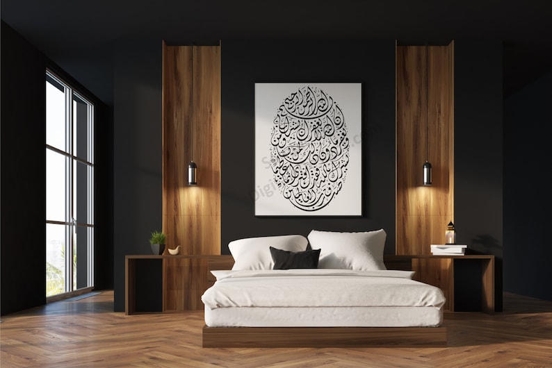 Op de afbeelding: Een wit bed met een wit dekbedovertrek en zwarte kussens staat in een moderne slaapkamer met donkere muren en houten accenten. Een grote zwart-witprint van Arabische kalligrafie hangt aan de muur boven het bed.