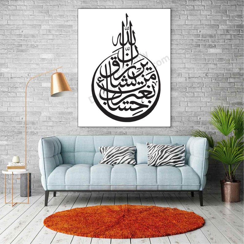 May include: A black and white calligraphy print of an Islamic prayer in a circular frame, hanging on a white wall above a light blue sofa with zebra print throw pillows. The print is in a living room setting with a gold lamp, a small table, and a potted plant.