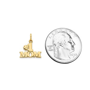 May include: Gold-tone pendant charm with the words "#1 MOM" in a bold font. The charm is about the size of a US quarter.