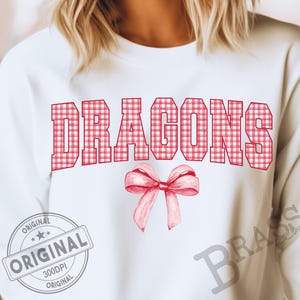 May include: White sweatshirt with the word "DRAGONS" in red gingham block letters and a watercolor bow. The sweatshirt also has a "ORIGINAL" stamp.