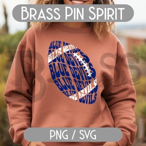 May include: A rust-colored sweatshirt featuring a blue and white football design with the words "BLUE DEVILS" repeated. The text "BRASS PIN SPIRIT" is above the design. The bottom of the image has the text "PNG / SVG".