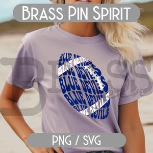 May include: A light purple t-shirt featuring a blue and white football design with the words "BLUE DEVILS" repeated throughout. The text "BRASS PIN SPIRIT" is above the shirt design. The bottom of the shirt has the text "PNG / SVG".