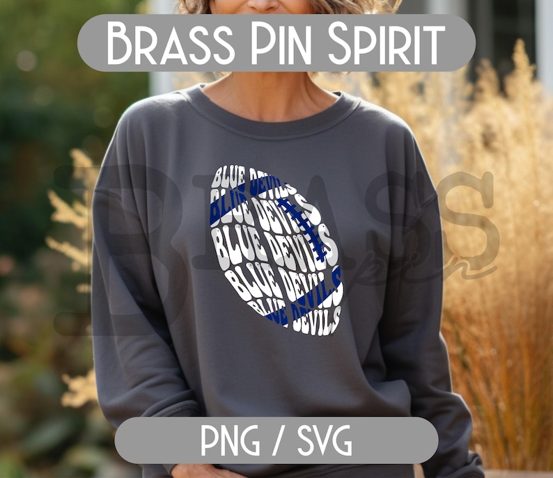 May include: A dark gray sweatshirt with a football-shaped graphic. The graphic features the words "BLUE DEVILS" in white and blue. The text "BRASS PIN SPIRIT" is above the sweatshirt, and "PNG / SVG" is below.
