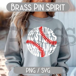 Puede incluir: Una sudadera gris con un dise&ntilde;o de b&eacute;isbol. El gr&aacute;fico de b&eacute;isbol presenta la palabra "Mustangs" en un patr&oacute;n circular, con detalles de costura rojos. El texto "Brass Pin Spirit" est&aacute; encima del dise&ntilde;o.