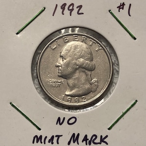 May include: A 1992 United States quarter dollar coin with the inscription "Liberty" on the obverse and "In God We Trust" on the reverse. The coin is in a plastic coin holder with the year 1992 and the number 1 printed on the holder. The holder also has the text "No Mint Mark" printed on it.