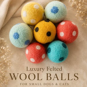 Peut inclure: Un ensemble de balles en laine feutrée colorées pour petits chiens et chats. Les balles sont dans des tons de jaune, rouge, bleu et vert, avec des pois blancs. Le texte "Luxury Felted Wool Balls" est affiché en dessous.