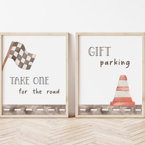 May include: Two framed prints with a racing theme. The first print features a checkered flag and the text "Take one for the road". The second print features a traffic cone and the text "Gift parking".