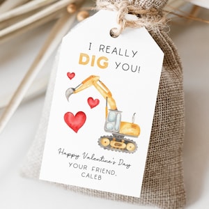 May include: A white gift tag with a yellow excavator digging up red hearts. The tag reads "I REALLY DIG YOU!" and "Happy Valentine's Day, YOUR FRIEND, CALEB."