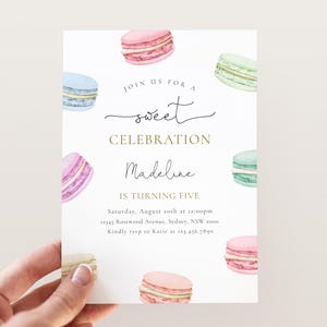 May include: A pastel pink, blue, and green birthday invitation with a watercolor illustration of macarons. The invitation reads "Join us for a sweet celebration Madeline is turning five. Saturday, August 20th at 12:00pm 12345 Rosewood Avenue, Sydney, NSW 2000 Kindly rsvp to Katie at 123.456.7890"