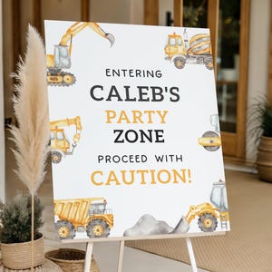 Puede incluir: Un letrero blanco sobre un caballete con el texto "Entering Caleb's Party Zone Proceed with Caution!" en negro y amarillo. El letrero est&aacute; decorado con ilustraciones de acuarela de veh&iacute;culos de construcci&oacute;n, incluyendo un cami&oacute;n volquete, una excavadora y una hormigonera.