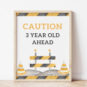 May include: A printable sign with a construction theme. It says "CAUTION 3 YEAR OLD AHEAD" with black and yellow striped barriers and orange traffic cones.