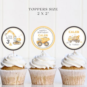 Op de afbeelding: Drie cupcake-toppers met een bouwvoertuigthema. De toppers zijn 5 cm bij 5 cm. Eén topper zegt "Ik vind het leuk om 3 te zijn" met een gele graafmachine. Een andere topper zegt "Gefeliciteerd met je verjaardag Caleb" met een gele kiepwagen. De derde topper zegt "Caleb is drie!" met een gele betonmixer.