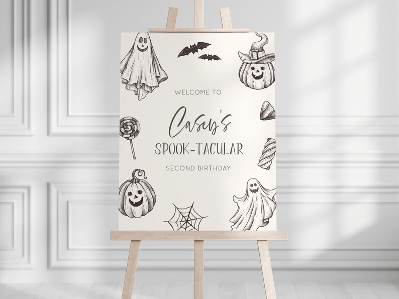 K&ouml;nnte beinhalten: Ein wei&szlig;es Willkommens-Schild mit schwarzen Illustrationen von Geistern, K&uuml;rbissen, Flederm&auml;usen, S&uuml;&szlig;igkeiten und einem Spinnennetz. Das Schild lautet "Willkommen zu Caseys Spook-tacular Second Birthday".