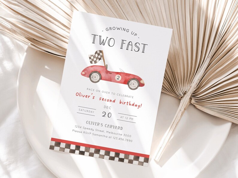 May include: A red race car with a checkered flag on top, a number 2 on the side, and the text "GROWING UP TWO FAST" at the top of the invitation. The invitation is for Oliver's second birthday party on December 20th at 12 PM. The invitation also includes the address and RSVP information.
