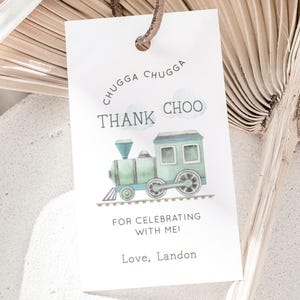 Puede incluir: Una etiqueta de agradecimiento blanca con una ilustración de acuarela de un tren verde y azul. La etiqueta dice "Chugga Chugga Choo ¡Gracias por celebrar conmigo! Con cariño, Landon".