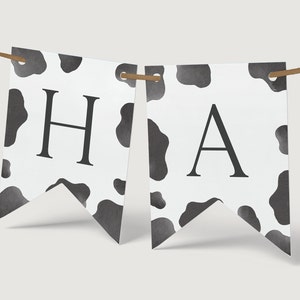 May include: A black and white cow print banner with the letters "HA" printed on it.