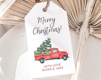 Puede incluir: Etiqueta de regalo blanca con una ilustración en acuarela de una camioneta roja que transporta un árbol de Navidad. La etiqueta dice "Merry Christmas!" y "With Love ELENA & JAKE". Está atada con una cuerda marrón.