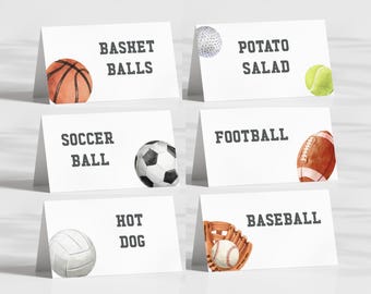 May include: White tent cards with watercolor illustrations of sports equipment. Cards include a basketball, golf ball, tennis ball, soccer ball, football, volleyball, baseball, and baseball glove. Text on the cards reads "Basket Balls", "Potato Salad", "Soccer Ball", "Football", "Hot Dog", and "Baseball".