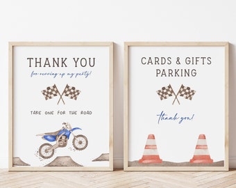 Puede incluir: Dos letreros enmarcados con un tema de motocross. Un letrero dice "GRACIAS" con una ilustración de motocicleta azul y banderas a cuadros. El otro letrero dice "TARJETAS Y REGALOS ESTACIONAMIENTO" con conos de tráfico y banderas a cuadros. Ambos letreros tienen texto.