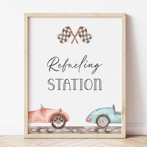 May include: A printable sign with a racing theme. It features two cartoon cars, chequered flags, and the text "Refueling Station".