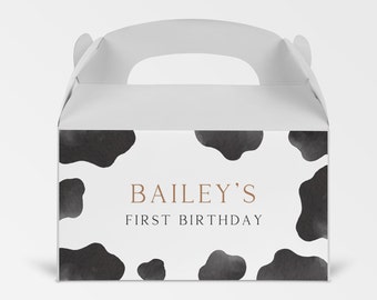 May include: White favor box with a black and white cow print design. The box has a handle and says "Bailey's First Birthday" in brown text.