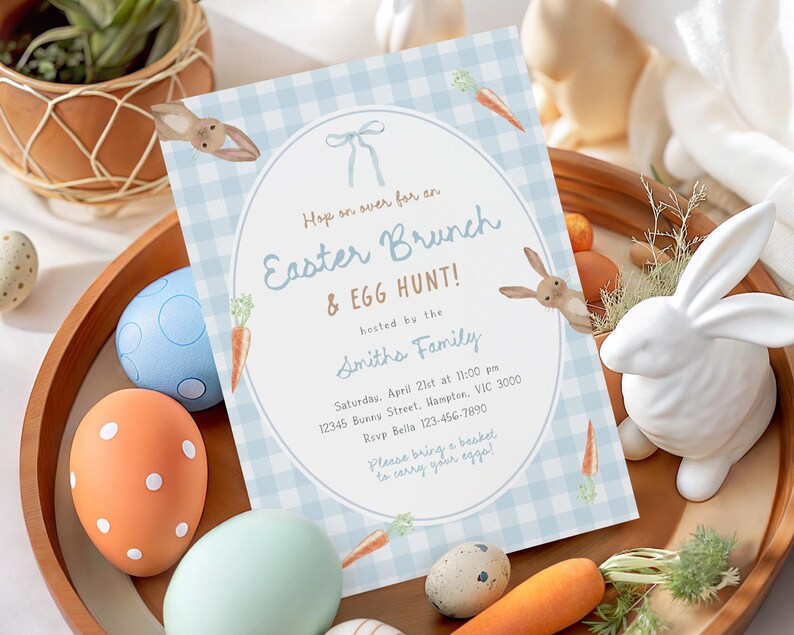 May include: An Easter Brunch & Egg Hunt invitation with a blue gingham background, bunny and carrot illustrations. The invitation is surrounded by decorative Easter eggs, a white ceramic bunny, and a wooden tray.