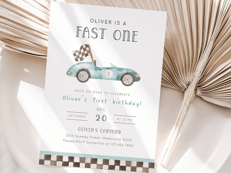 May include: A blue and white birthday invitation with a cartoon race car and the text "Oliver is a Fast One". The invitation says "Race on over to celebrate Oliver's first birthday!" and includes the date, time, and location of the party.