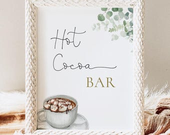 Könnte beinhalten: Ein weißer gerahmter Schild mit dem Text "Hot Cocoa Bar" in schwarzer Schreibschrift. Eine Aquarell-Illustration einer Tasse heißer Schokolade mit Marshmallows befindet sich in der rechten unteren Ecke.