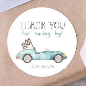 May include: Round thank you sticker featuring a blue racing car and chequered flag. The sticker reads "Thank you for racing by! Love, Oliver".