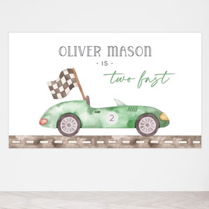 May include: Green watercolor illustration of a race car with a checkered flag on a brown road. The text "Oliver Mason - is - two fast" is written above the car.