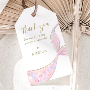 May include: White thank you tag with gold text that says "Thank you for making my party a splash!" with a pink and blue mermaid tail illustration and the name Amelia in gold text.