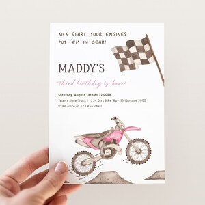 May include: A pink and white birthday invitation with a checkered flag and a pink dirt bike. The invitation says "Maddy's third birthday is here!" and includes the date, time, and location of the party. RSVP information is also included.
