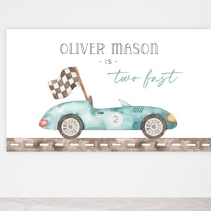 May include: A blue watercolor illustration of a race car with a checkered flag on top. The car is on a brown road with a white dashed line. The text "Oliver Mason - is - two fast" is written above the car.