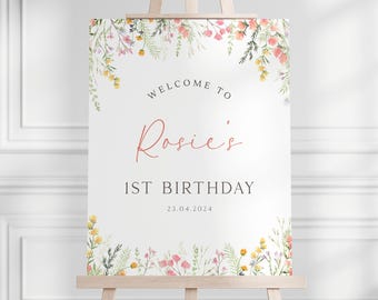 May include: A white sign with a floral border and the text "Welcome to Rosie's 1st Birthday 23.04.2024".