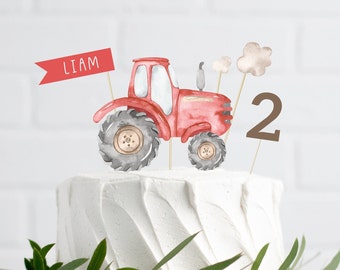 Könnte beinhalten: Roter und grauer Traktor-Kuchentopper mit einem Banner, auf dem "LIAM" steht, und einer braunen Zahl "2" auf einem weiß glasierten Kuchen.