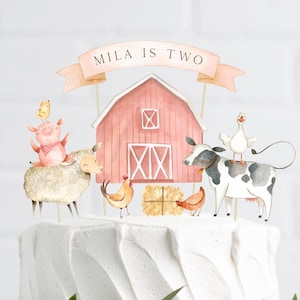 Pode incluir: Um topo de bolo de celeiro vermelho com uma faixa branca que diz "Mila is Two". O topo também inclui um porco, uma ovelha, uma vaca, um ganso e galinhas.