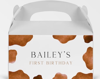 May include: White favor box with a brown cow print design. The box has a handle and says "BAILEY'S FIRST BIRTHDAY" on the front.